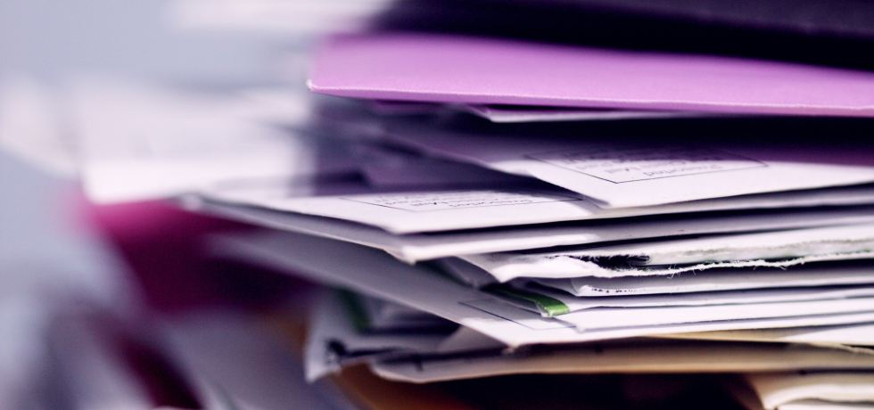 A pile of mail including coloured envelopes.