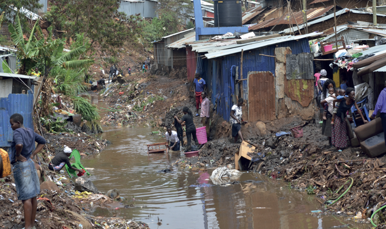 A group of people standing in a stream with informal settlements either side.