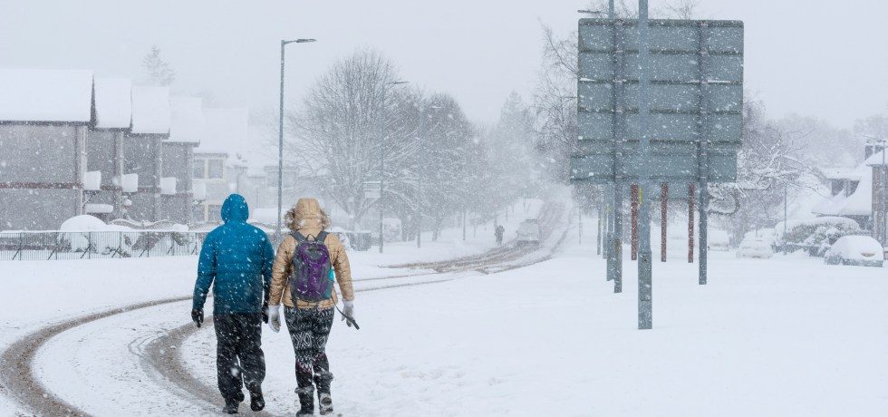 Two people walking on a snowy road.